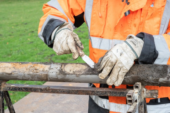 Hohlgestänge mit Bodenprobe mit Mensch in Arbeitsjacke