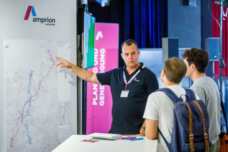 Projektsprecher Florian Zettel zeigt auf eine Karte und sieht dabei zwei Personen an.